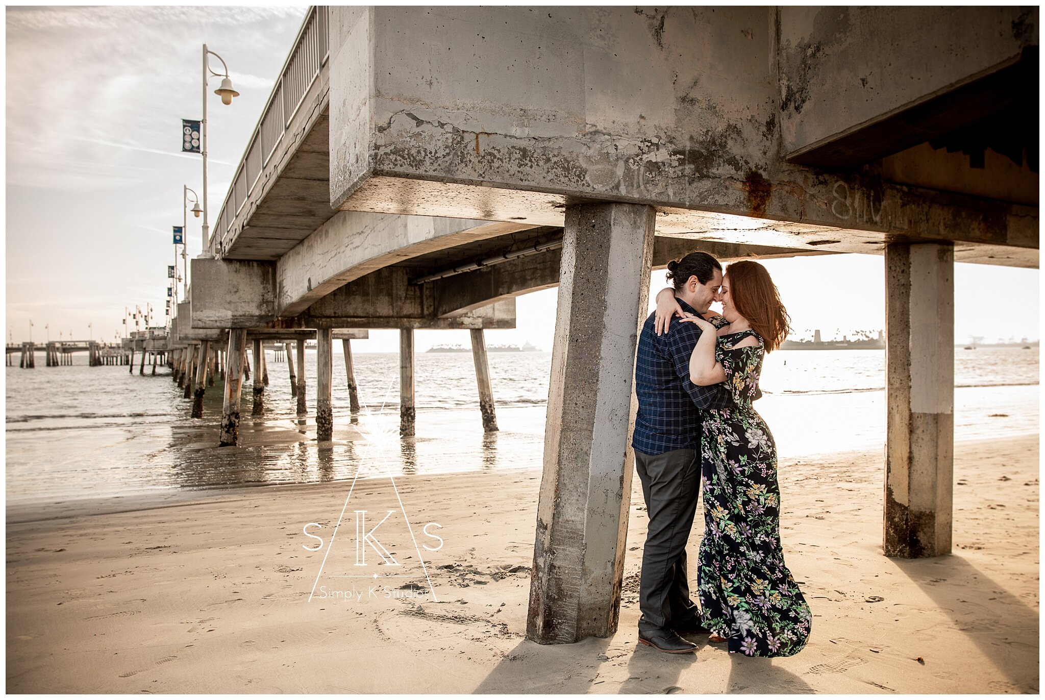  Couple kissing at the beach near a pier 