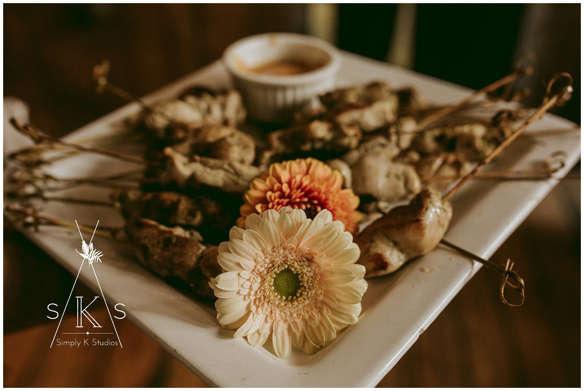  chicken skewers on a tray with a peach flower in front 