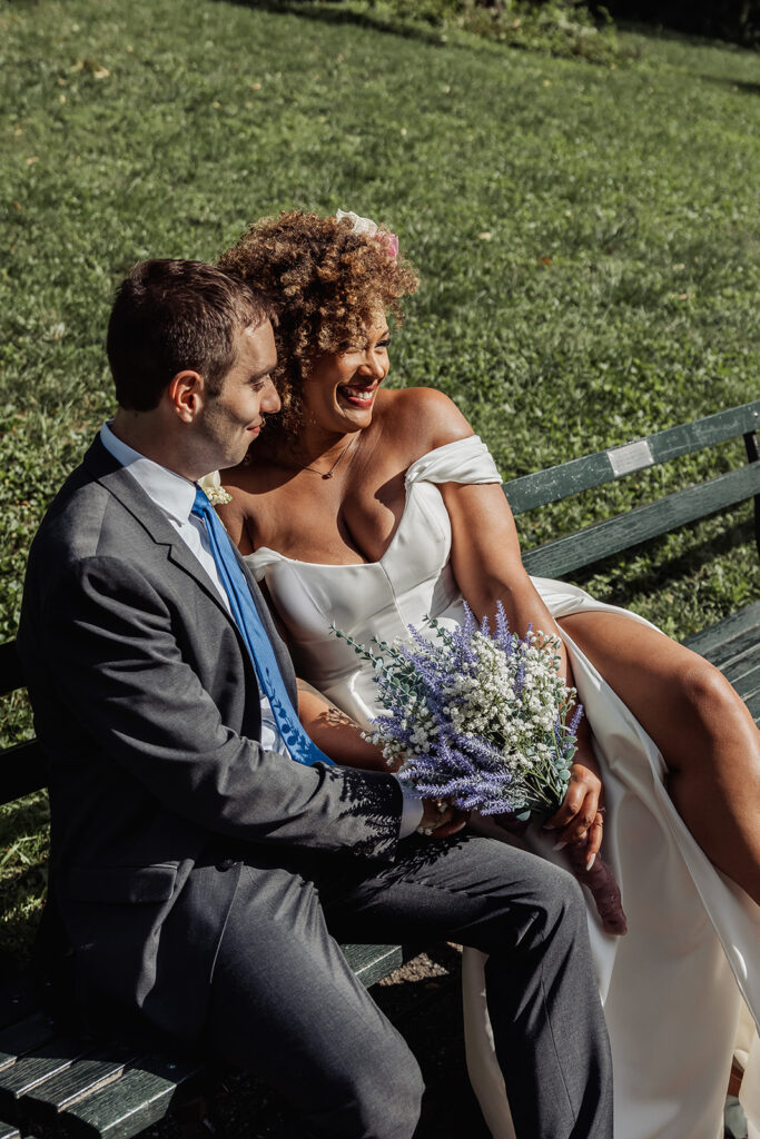 bride and groom sitting on a bench in central park