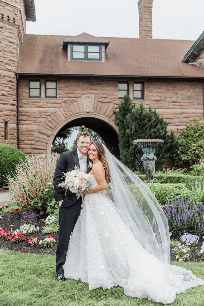 beautiful bride and groom with OceanCliff, a Newport wedding venue, in the backdrop